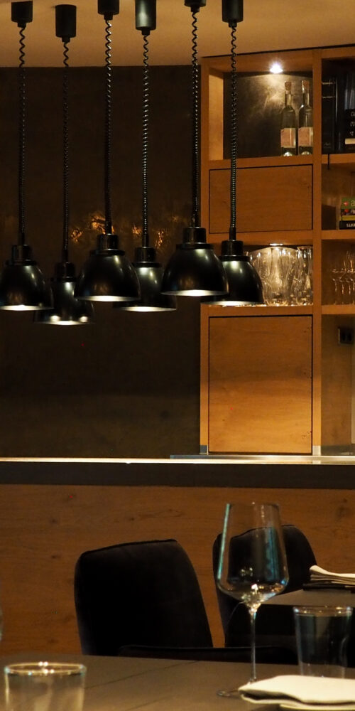 Aufnahme des Restaurants Genusswerkstatt mit dem Blick über die eingedeckten Tische hinweg zur Anrichtefläche