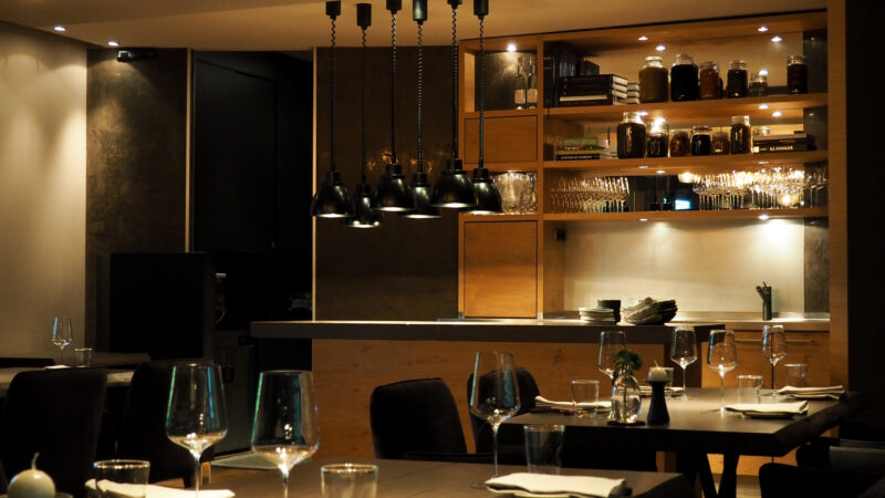Aufnahme des Restaurants Genusswerkstatt mit dem Blick über die eingedeckten Tische hinweg zur Anrichtefläche
