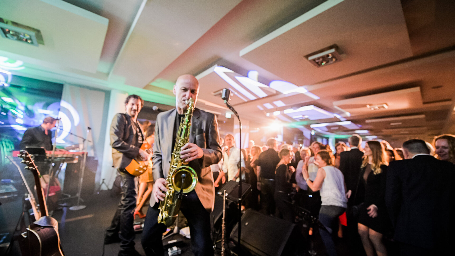 Partybild aufgenommen aufunserer großen Tastetival Wein und Genussparty im Foyer vor den Veranstaltungsräumen D1-D3 im Vordergrund eine Band auf der Bühne zu sehen im Hintergrund eine Menschenmenge beim Tanzen