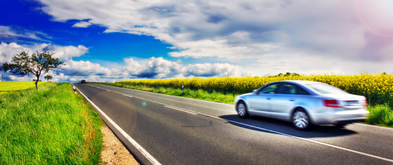 Auto fährt auf einer Landstraße über das Land