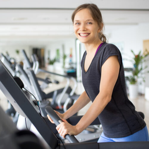 Lächelnde sportliche Frau Training auf dem Laufband im Fitnessstudio