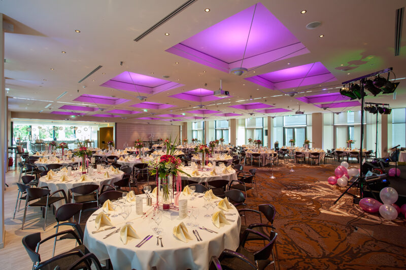 Veranstaltungsraum E1, E2 und E3 kombiniert aufgenommen aus der hinteren rechten Ecke, zu sehen eine klassische Bankett Bestuhlung an runden Tischen schön dekoriert und eingedeckt für eine große Hochzeit