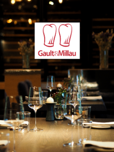 Auszeichnung Gault&Millau Logo mit Hintergrundbild aus unserer Genusswerkstatt und der Bewertung zwei roten Hauben