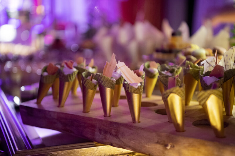 Detail Foto eines Dessertganges auf dem Buffet, zu sehen Eiswaffeln in goldenen Papier umwickelt angerichtet auf einem Holzbrett mit süßem Inhalt
