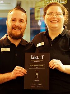 Urkunde der falstaff Bewertung präsentiert von Dennis Schmidt und Kathrin Hurstjes die die Urkunde halten